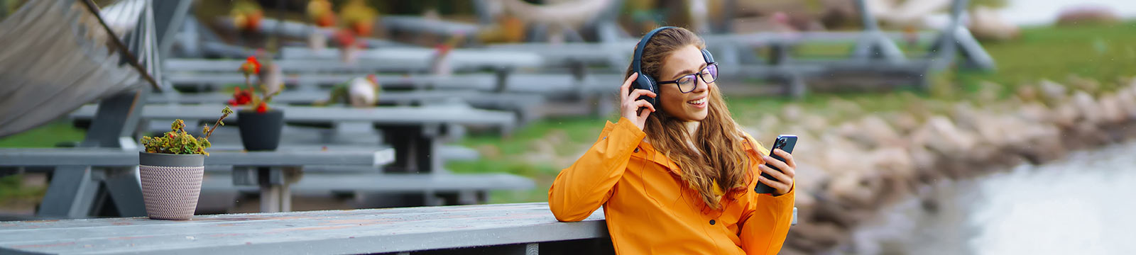 Woman looking at phone sitting near a lake.